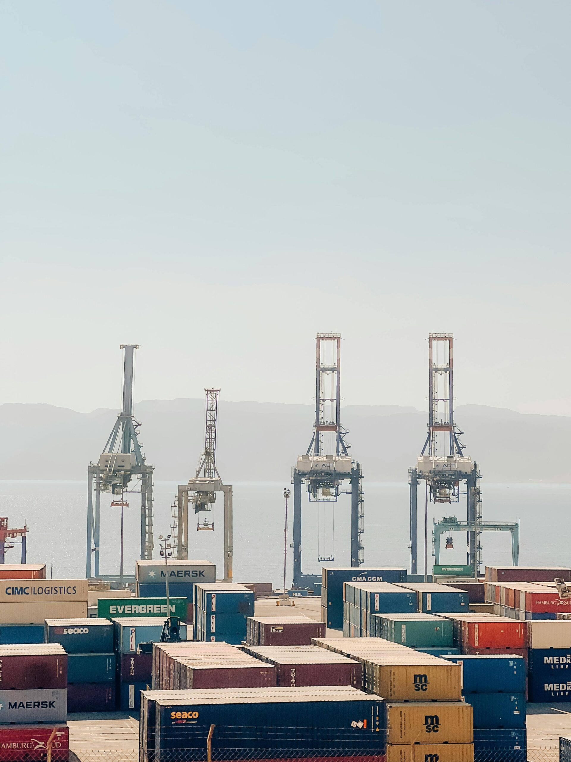 Cranes and shipping containers at Aqaba Port, Jordan, on a clear day.