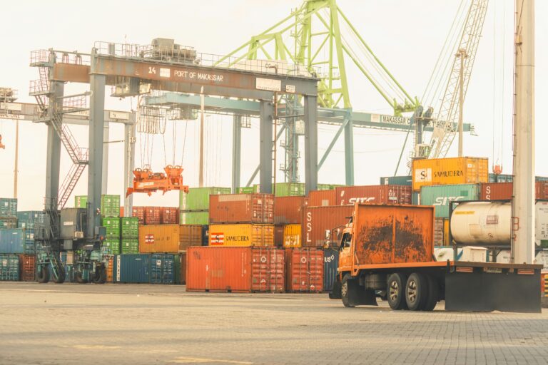Busy cargo terminal at the Port of Makassar with containers and cranes, vibrant industrial scene.