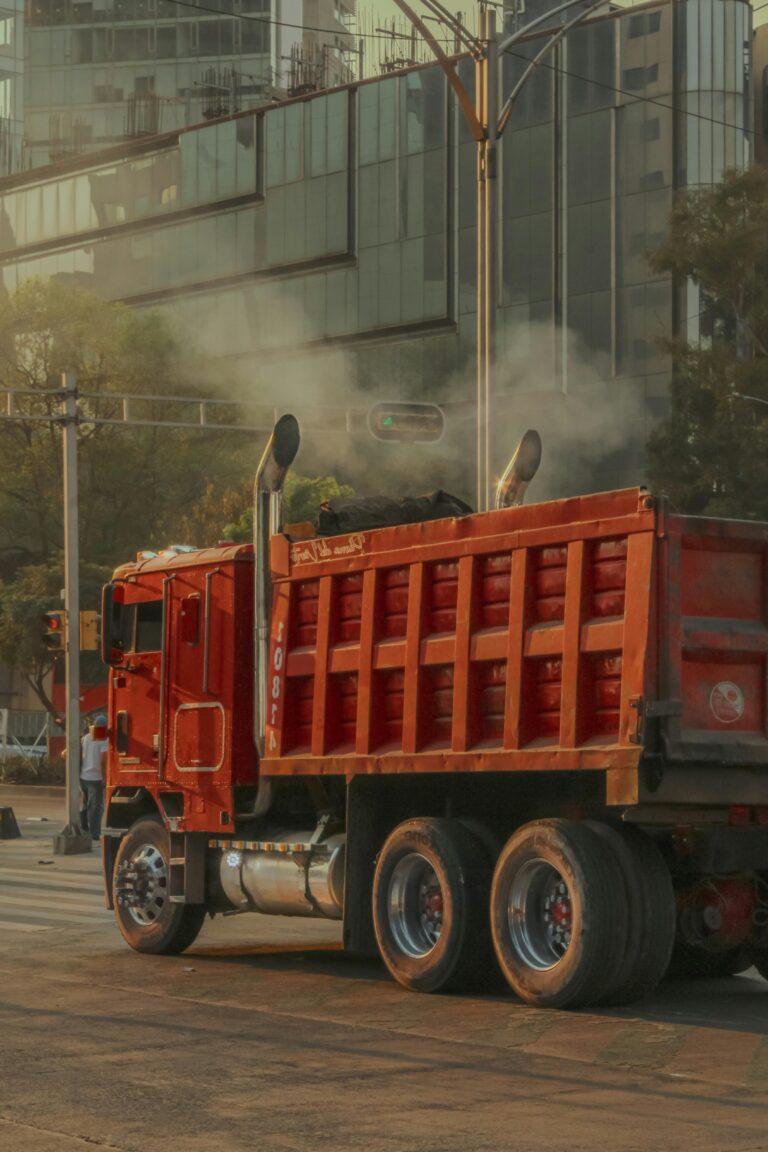 A red truck on a busy street in Ciudad de México, showcasing urban life and city architecture.